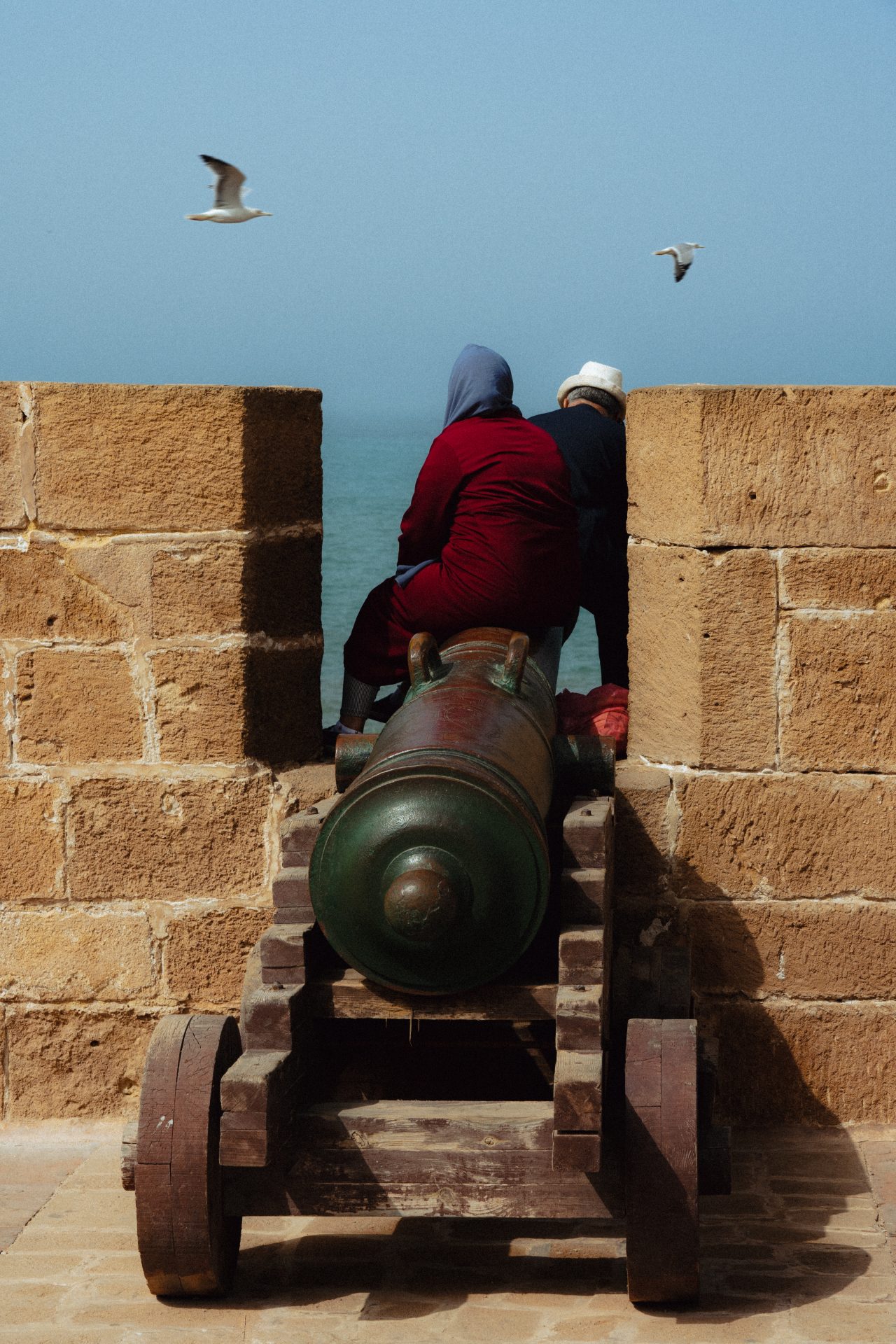 Un couple est assis sur un canon sur les murailles d'Essaouira