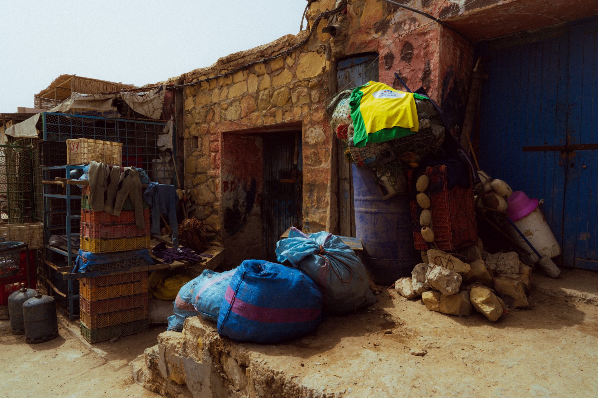 De nombreux sacs et affaires devant une petite maison sur le port d'Imsouane